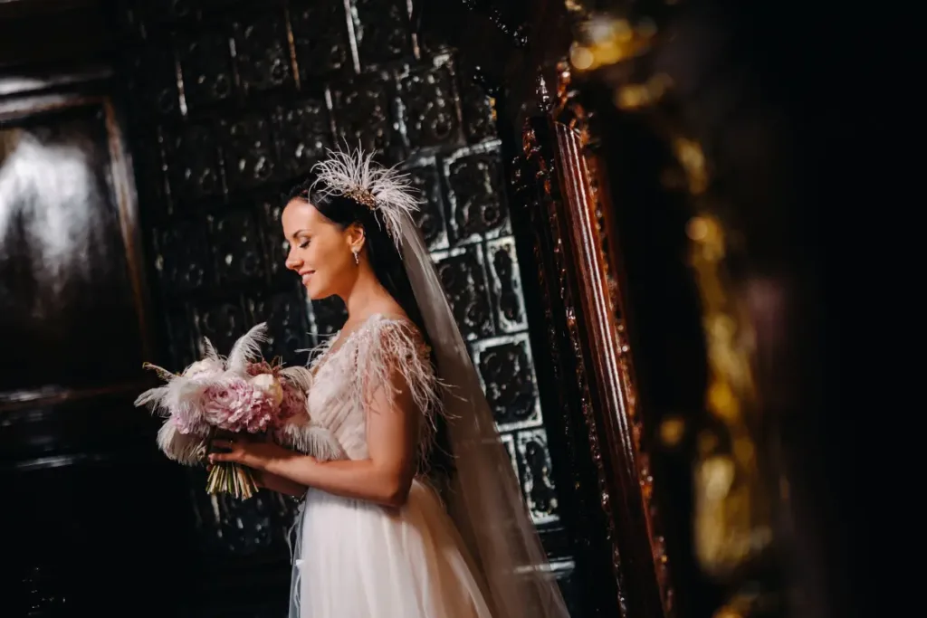 Wedding Aesthetic: How to Choose a Style That Shapes the Entire Experience Bride holding a bouquet in a dark, moody setting that emphasizes texture, lighting contrast, and a dramatic wedding style